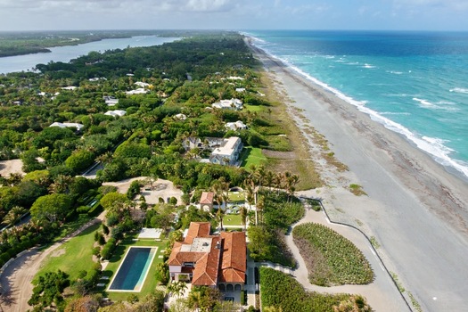 Aerial view of the contrasting hues of the ocean meeting the sandy shore lush greenery blending with luxurious estates Jupiter Island Florida United States. Aerial view of the contrasting hues of the ocean meeting the sandy shore lush greenery blending with luxurious estates Jupiter Island Florida United States.