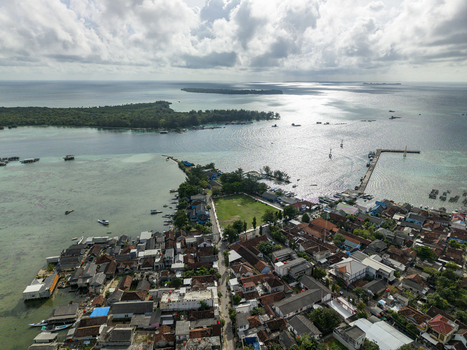 Aerial view of the town square blending into the sea with boats dotting the horizon under a sky streaked with clouds Karimunjawa Central Java Indonesia. Aerial view of the town square blending into the sea with boats dotting the horizon under a sky streaked with clouds Karimunjawa Central Java Indonesia.