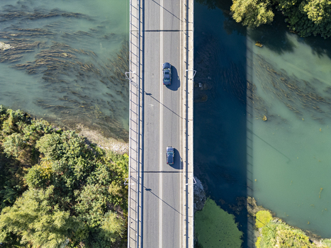 Aerial view of Ura e re e Bunes with cars driving across the bridge over the river surrounded by lush green trees in Shkoder Qarku i Shkodres Albania. Aerial view of Ura e re e Bunes with cars driving across the bridge over the river surrounded by lush green trees in Shkoder Qarku i Shkodres Albania.
