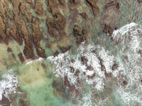 Aerial view of the Hartenbos coastline with waves crashing against jagged rocks and clear turquoise water in Mossel Bay Western Cape South Africa. Aerial view of the Hartenbos coastline with waves crashing against jagged rocks and clear turquoise water in Mossel Bay Western Cape South Africa.
