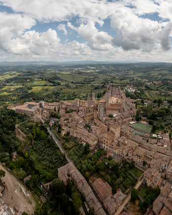 Aerial view of San Gimignano with its iconic medieval towers rising above historic stone rooftops surrounded by rolling hills and vineyards in San Gimignano Tuscany Italy. Aerial view of San Gimignano with its iconic medieval towers rising above historic stone rooftops surrounded by rolling hills and vineyards in San Gimignano Tuscany Italy.