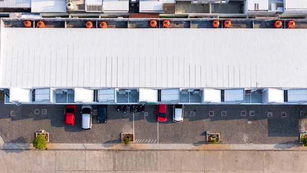 Aerial view of a long building with a white corrugated metal roof orange water tanks and parked cars in the parking lot in Semarang Central Java Indonesia. Aerial view of a long building with a white corrugated metal roof orange water tanks and parked cars in the parking lot in Semarang Central Java Indonesia.
