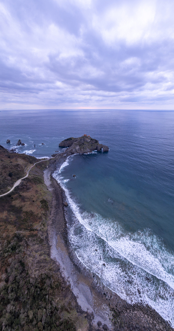 Aerial view of San Juan de Gaztelugatxe a historic hermitage on a rocky islet with a winding stone bridge surrounded by the Cantabrian Sea in Gaztelugatxeko Doniene Euskadi Spain.