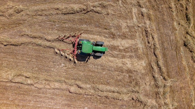 Aerial view of a green tractor working in a dry harvested field in Philadelphia Western Cape South Africa. Aerial view of a green tractor working in a dry harvested field in Philadelphia Western Cape South Africa.