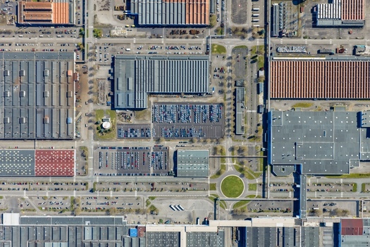 Aerial view of industrial buildings with organized parking lots and roads contrasting with the green circle in the center Sausheim Grand Est France.
