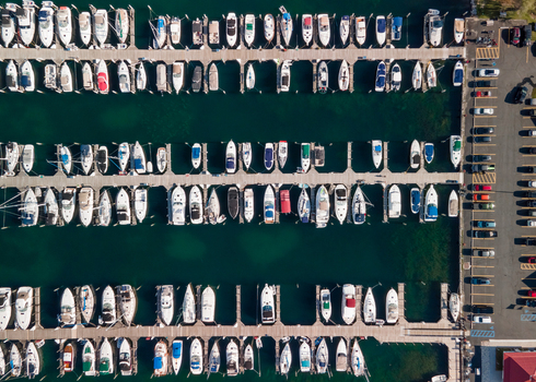 Aerial view of numerous boats docked in slips at a marina with wooden piers and a parking lot in Traverse City Michigan United States.