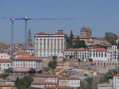 View of the historic cityscape of Porto with traditional buildings orange tiled rooftops and construction cranes under a clear blue sky in Porto Porto District Portugal. View of the historic cityscape of Porto with traditional buildings orange tiled rooftops and construction cranes under a clear blue sky in Porto Porto District Portugal.
