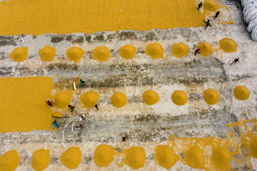 Brahmanbaria Bangladesh 15 August 2021 Aerial view of workers spreading and drying harvested rice in piles on a concrete surface.