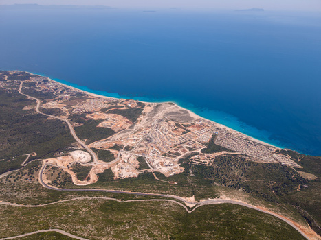 Aerial view of the turquoise coastline with a winding mountain road and new construction projects near the beach in Palase Vlore County Albania.