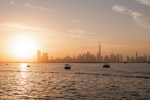 View of the Burj Khalifa and the modern city skyline at sunset with small boats on the water Dubai Dubai United Arab Emirates. View of the Burj Khalifa and the modern city skyline at sunset with small boats on the water Dubai Dubai United Arab Emirates.