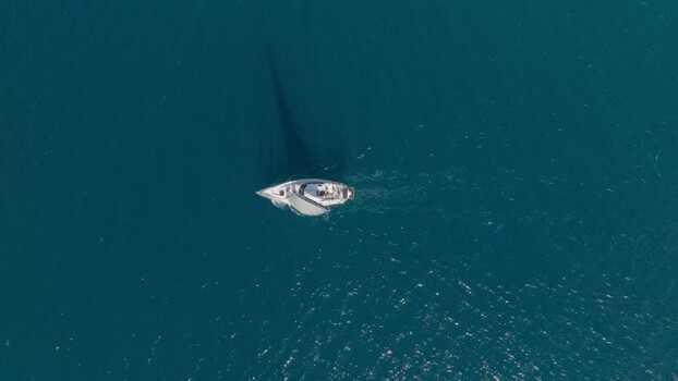 Aerial view of a sailboat sailing on blue water Italy.