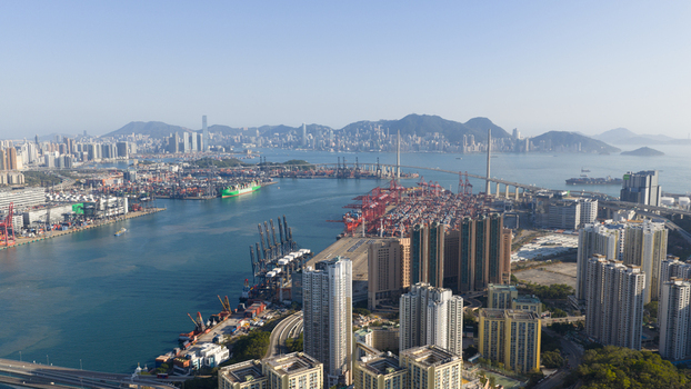 Aerial view of the busy Kwai Tsing Container Terminals with Stonecutters Bridge and high rise residential buildings under a clear sky in Hong Kong Hong Kong. Aerial view of the busy Kwai Tsing Container Terminals with Stonecutters Bridge and high rise residential buildings under a clear sky in Hong Kong Hong Kong.