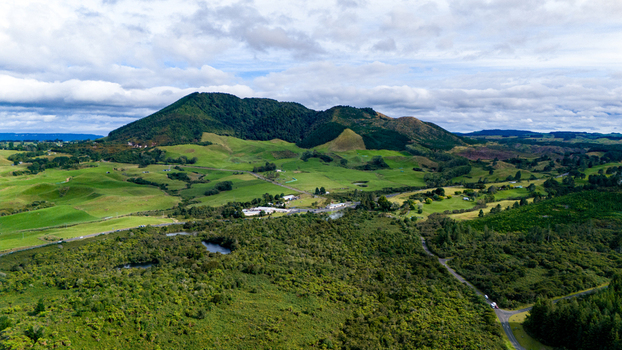 Aerial view of rolling green hills meet the dense forest under a bright sky Waiotapu Thermal Wonderland Waikato Region New Zealand. Aerial view of rolling green hills meet the dense forest under a bright sky Waiotapu Thermal Wonderland Waikato Region New Zealand.