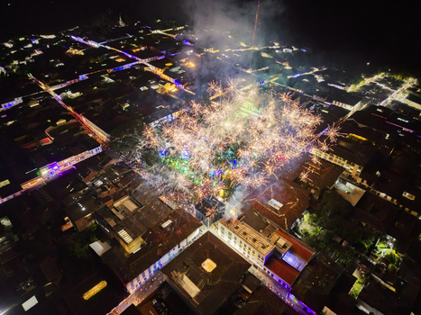 Aerial view of a town square illuminated by a burst of fireworks casting a warm glow over the dark buildings Salamina Caldas Colombia. Aerial view of a town square illuminated by a burst of fireworks casting a warm glow over the dark buildings Salamina Caldas Colombia.