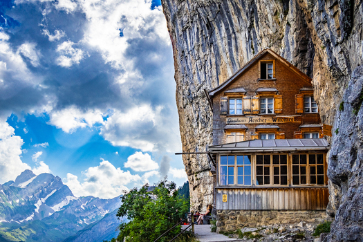View of a wooden house clinging to a cliff face a testament to human ingenuity against a backdrop of jagged peaks Schwende Rüte Appenzell Innerrhoden Switzerland. View of a wooden house clinging to a cliff face a testament to human ingenuity against a backdrop of jagged peaks Schwende Rüte Appenzell Innerrhoden Switzerland.