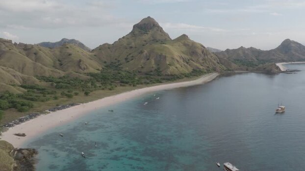 Aerial view of Komodo Island with green hills and boats Indonesia.