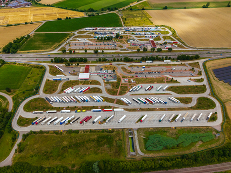 Aerial view of Serways Raststatte Hohenlohe Sud truck stop with many semi trucks parked in bays surrounded by agricultural fields and green landscape in Neuenstein Baden Wurttemberg Germany. Aerial view of Serways Raststatte Hohenlohe Sud truck stop with many semi trucks parked in bays surrounded by agricultural fields and green landscape in Neuenstein Baden Wurttemberg Germany.