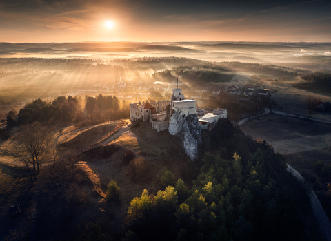 Aerial view of Rabsztyn Castle ruins on a rocky hill during a misty sunrise with golden light rays over the Krakow Czestochowa Upland Krakow County Lesser Poland Voivodeship Poland. Aerial view of Rabsztyn Castle ruins on a rocky hill during a misty sunrise with golden light rays over the Krakow Czestochowa Upland Krakow County Lesser Poland Voivodeship Poland.