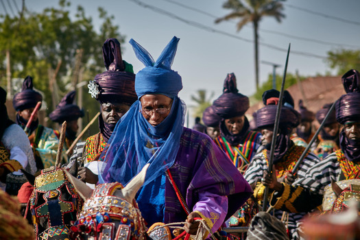 Zaria city Nigeria 21 March 2026 View of a majestic cultural parade with figures in resplendent blue and purple traditional attire rich textures under a bright sky. Zaria city Nigeria 21 March 2026 View of a majestic cultural parade with figures in resplendent blue and purple traditional attire rich textures under a bright sky.
