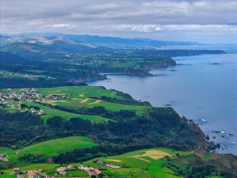 Aerial view of Silence Beach Viewpoint with rugged cliffs lush green meadows and coastal villages in Cudillero Asturias Spain.