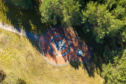 Aerial view of The Geographical Centre Of Europe monument featuring a large compass rose plaza and a white column with a golden crown surrounded by lush forest Girija Vilnius County Lithuania. Aerial view of The Geographical Centre Of Europe monument featuring a large compass rose plaza and a white column with a golden crown surrounded by lush forest Girija Vilnius County Lithuania.