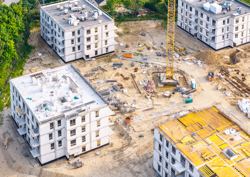 Aerial view of a residential construction site featuring several multi story buildings a yellow tower crane and raw earth ground in Kowale Pomeranian Voivodeship Poland. Aerial view of a residential construction site featuring several multi story buildings a yellow tower crane and raw earth ground in Kowale Pomeranian Voivodeship Poland.