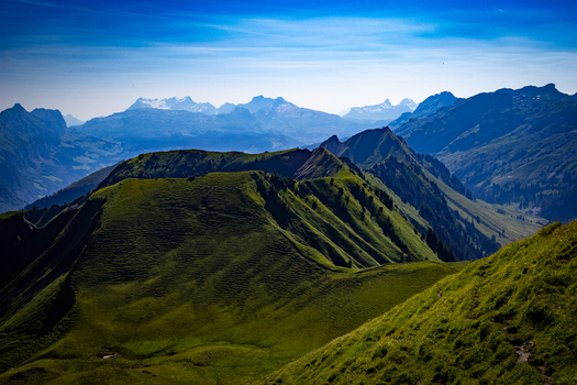 Aerial view of sun drenched velvety green slopes cascading towards the distant hazy blue mountains a symphony of nature s grandeur Morschach Schwyz Switzerland. Aerial view of sun drenched velvety green slopes cascading towards the distant hazy blue mountains a symphony of nature s grandeur Morschach Schwyz Switzerland.