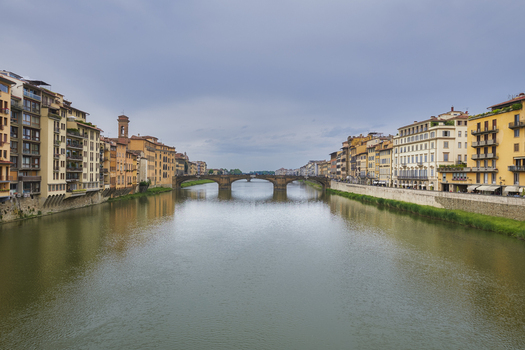 Florence Italy 05 May 2022 View of the historic Ponte Vecchio bridge spanning the Arno River surrounded by traditional buildings under a cloudy sky in Florence Italy. Florence Italy 05 May 2022 View of the historic Ponte Vecchio bridge spanning the Arno River surrounded by traditional buildings under a cloudy sky in Florence Italy.