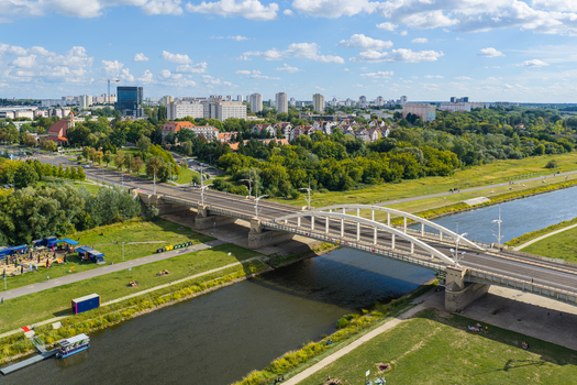 Aerial view of the Boleslaw Chrobry Bridge spanning the Warta river in Poznan with green banks urban parkland and city skyline in Poznan Greater Poland Voivod Poland.