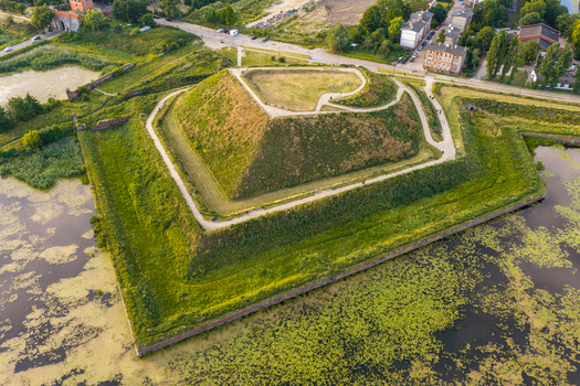 Aerial view of the historic star shaped fortification with green grassy ramparts and a moat filled with water lilies in Gdansk Pomeranian Voivodeship Poland. Aerial view of the historic star shaped fortification with green grassy ramparts and a moat filled with water lilies in Gdansk Pomeranian Voivodeship Poland.