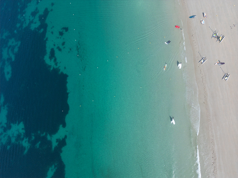 Aerial view of the sandy beach and turquoise sea with small boats and people on the shore in Trebeurden Brittany France. Aerial view of the sandy beach and turquoise sea with small boats and people on the shore in Trebeurden Brittany France.