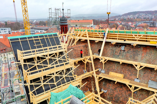 Aerial view of Rathaus Forchheim under renovation with workers on wooden scaffolding and a crane hook lowering a beam in Forchheim Bayern Germany. Aerial view of Rathaus Forchheim under renovation with workers on wooden scaffolding and a crane hook lowering a beam in Forchheim Bayern Germany.