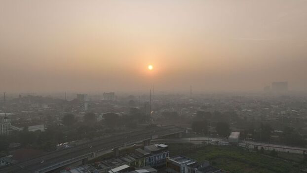 Aerial view of the urban landscape of Bekasi Barat at sunset with a hazy atmosphere visible highway and dense rooftops in Bekasi Barat West Java Indonesia. Aerial view of the urban landscape of Bekasi Barat at sunset with a hazy atmosphere visible highway and dense rooftops in Bekasi Barat West Java Indonesia.