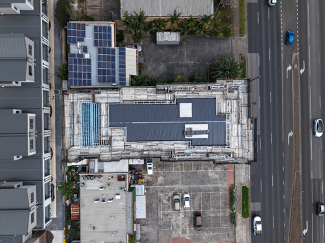 Melbourne VIC Australia 25 September 2026 Aerial view of a building under construction with scaffolding solar panels on an adjacent roof and a parking lot.