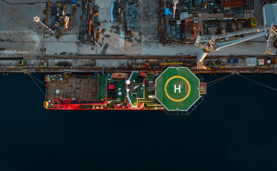 Aerial view of the Uljanik Shipyard featuring a large vessel with a helipad docked at the industrial harbor in Pula Croatia. Aerial view of the Uljanik Shipyard featuring a large vessel with a helipad docked at the industrial harbor in Pula Croatia.