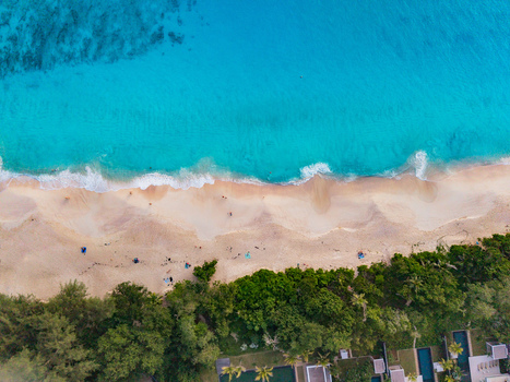 Aerial view of the turquoise ocean meeting the sandy shore fringed by verdant trees and modern villas Quatre Bornes Mahe Island Seychelles. Aerial view of the turquoise ocean meeting the sandy shore fringed by verdant trees and modern villas Quatre Bornes Mahe Island Seychelles.