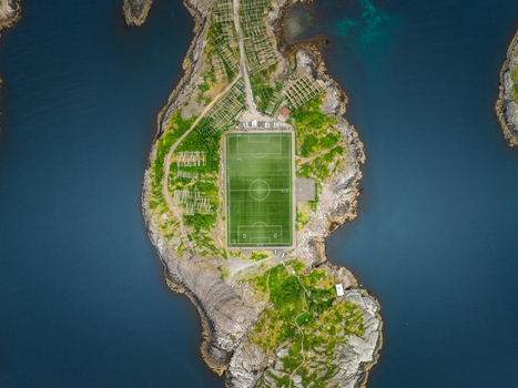 Aerial view of Henningsvaer Football Stadium situated on a rocky island surrounded by deep blue sea and rugged terrain in Henningsvaer Nordland Norway.