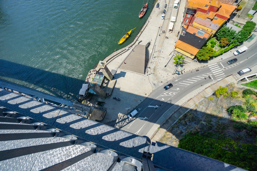 Aerial view of the Douro River s edge where the Dom Luís I Bridge s shadow stretches across the scene contrasting with the vibrant buildings of Porto Porto Portugal. Aerial view of the Douro River s edge where the Dom Luís I Bridge s shadow stretches across the scene contrasting with the vibrant buildings of Porto Porto Portugal.