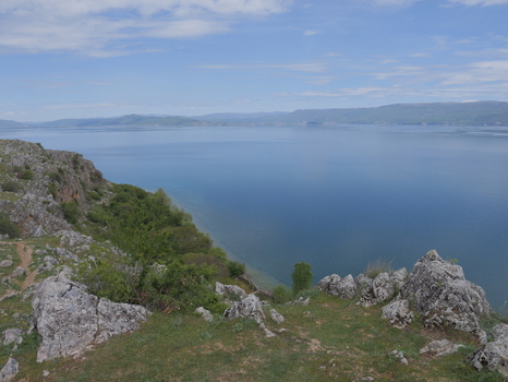 View of the rocky terrain and hills overlooking the expansive blue waters of Lake Ohrid in Lin Korce County Albania.