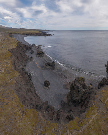 Aerial view of Djupalonssandur black sand beach with dramatic volcanic rock formations rugged cliffs and the Atlantic Ocean under a cloudy sky in Iceland. Aerial view of Djupalonssandur black sand beach with dramatic volcanic rock formations rugged cliffs and the Atlantic Ocean under a cloudy sky in Iceland.