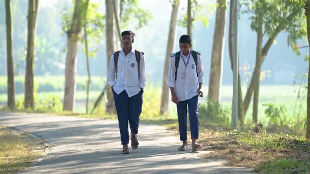 View of schoolboys walking on a rural road in Bogura Bangladesh.
