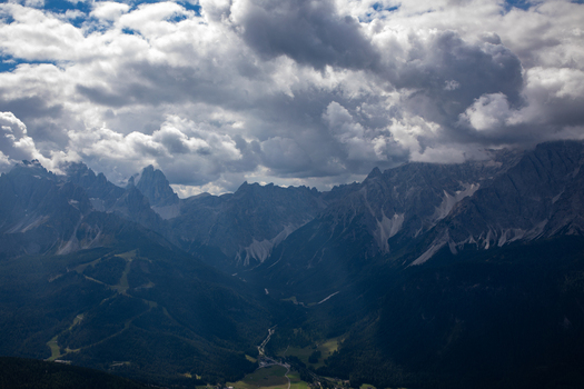 View of the jagged peaks of the Dolomites under a dramatic cloudy sky with deep valleys and dense evergreen forests in the Italian Alps Rocca Pietore Veneto Italy. View of the jagged peaks of the Dolomites under a dramatic cloudy sky with deep valleys and dense evergreen forests in the Italian Alps Rocca Pietore Veneto Italy.
