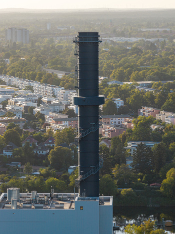 Aerial view of the Lichterfelde power plant chimney rising above residential buildings and lush green trees in the urban landscape of Berlin Berlin Germany. Aerial view of the Lichterfelde power plant chimney rising above residential buildings and lush green trees in the urban landscape of Berlin Berlin Germany.