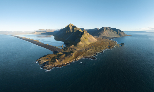 Aerial view of a rugged peninsula stretches into the sea crowned by majestic mountains against a serene sky Hvalnes Sveitarfélagið Hornafjörður Iceland. Aerial view of a rugged peninsula stretches into the sea crowned by majestic mountains against a serene sky Hvalnes Sveitarfélagið Hornafjörður Iceland.