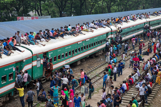 Dhaka Bangladesh 15 June 2018 View of Airport Railway Station crowded with people sitting on train roofs and standing on tracks during Eid al Fitr travel rush. Dhaka Bangladesh 15 June 2018 View of Airport Railway Station crowded with people sitting on train roofs and standing on tracks during Eid al Fitr travel rush.