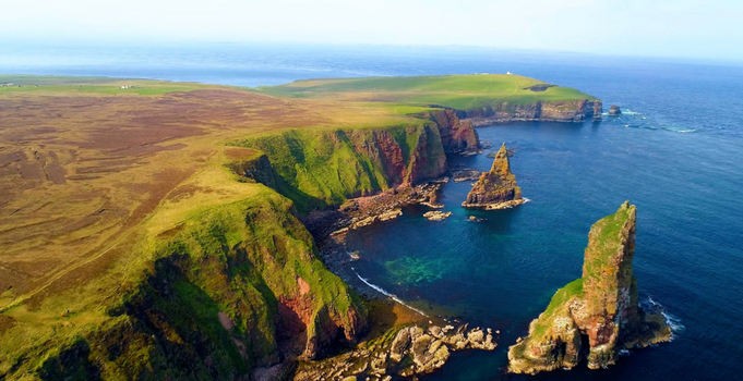 Aerial view of Duncansby Stacks with rugged cliffs and green grassy landscape John o Groats Highland Council United Kingdom. Aerial view of Duncansby Stacks with rugged cliffs and green grassy landscape John o Groats Highland Council United Kingdom.