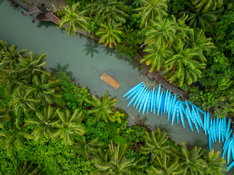 Aerial view of Coconut river with lush palm trees a wooden dock and numerous blue boats moored along the bank in Siargao Philippines. Aerial view of Coconut river with lush palm trees a wooden dock and numerous blue boats moored along the bank in Siargao Philippines.
