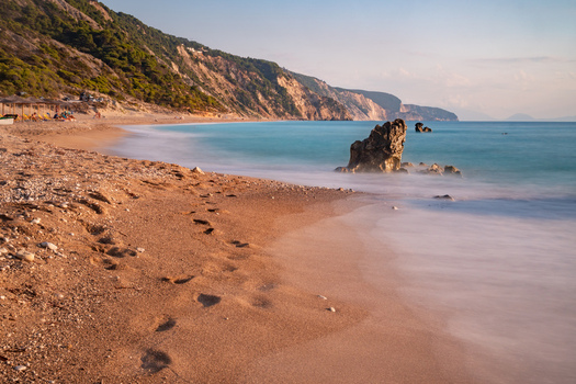 View of golden sand meeting the turquoise waters under the watchful gaze of cliffside greenery a serene coastal panorama Lefkada Greece. View of golden sand meeting the turquoise waters under the watchful gaze of cliffside greenery a serene coastal panorama Lefkada Greece.