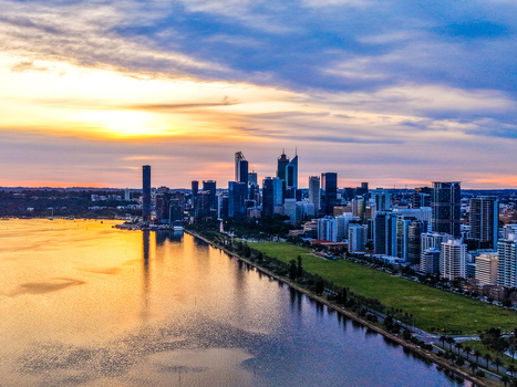 Aerial view of the Perth skyline at sunset with high rise buildings reflecting in the Swan River under a vibrant sky in Perth Western Australia Australia.
