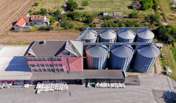Aerial view of the storage silo Bavaniste with its large metallic grain bins and adjacent pink industrial building surrounded by agricultural fields in Bavaniste Vojvodina Serbia.